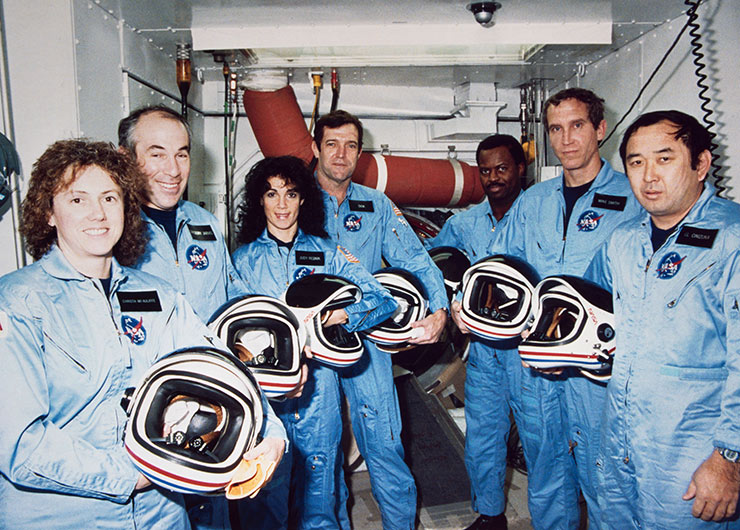 Crew of STS-51L, wearing blue suits and holding helmets.
