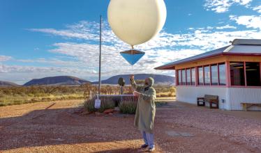 A person prepares to release a white weather balloon. 