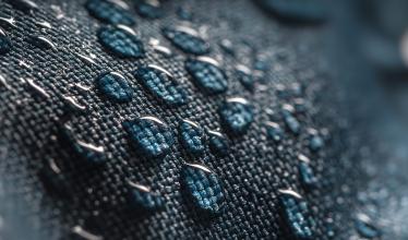 Close up of numerous water droplets on dark blue woven fabric