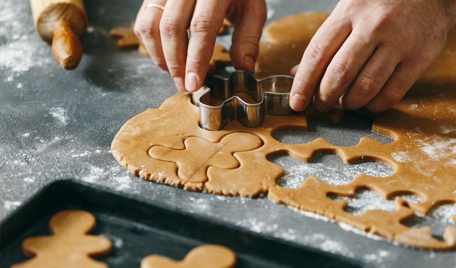 Hands cutting gingerbread cookies