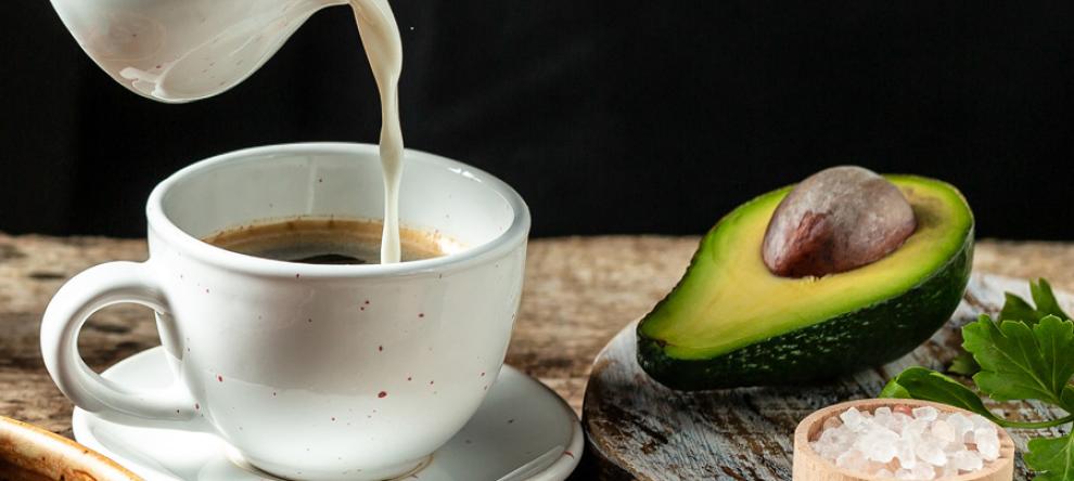 A cup of coffee next to a half avocado
